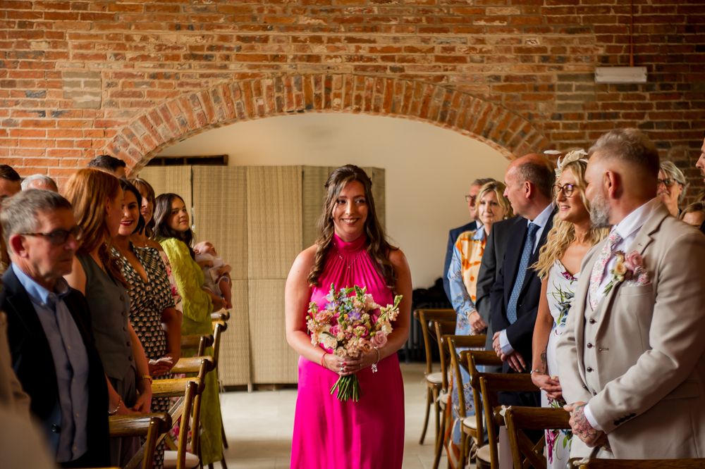 Wedding celebration in progress inside a charming brick-walled venue with arched windows.