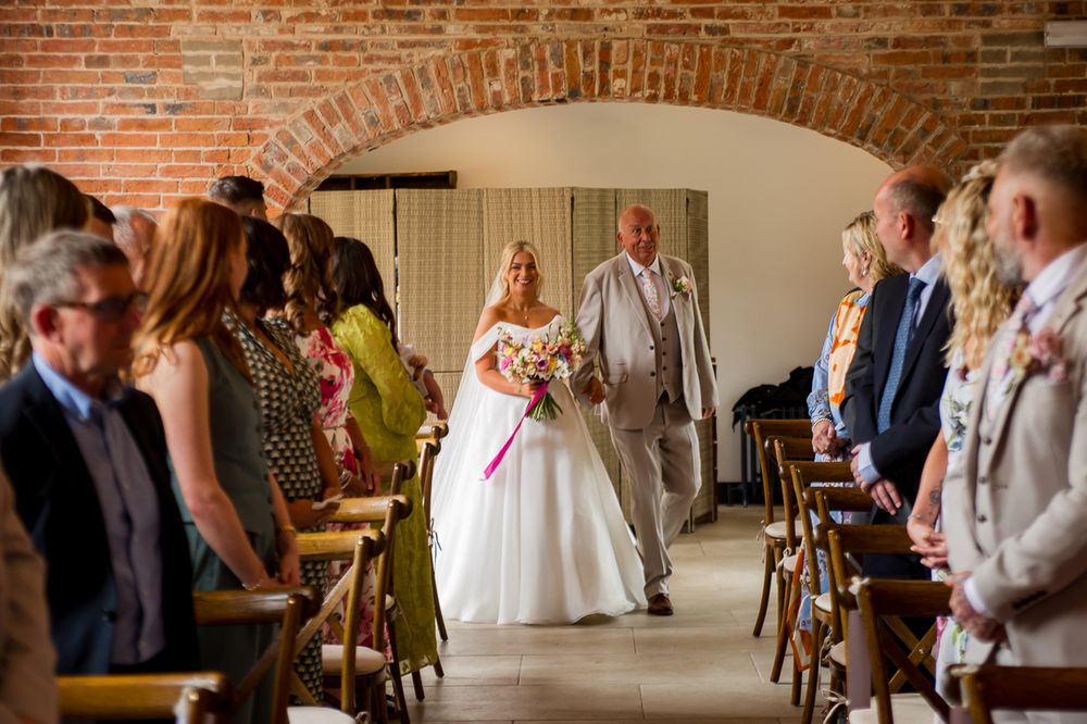 Guests gather in an elegant brick-walled reception space with vaulted ceilings and natural lighting.