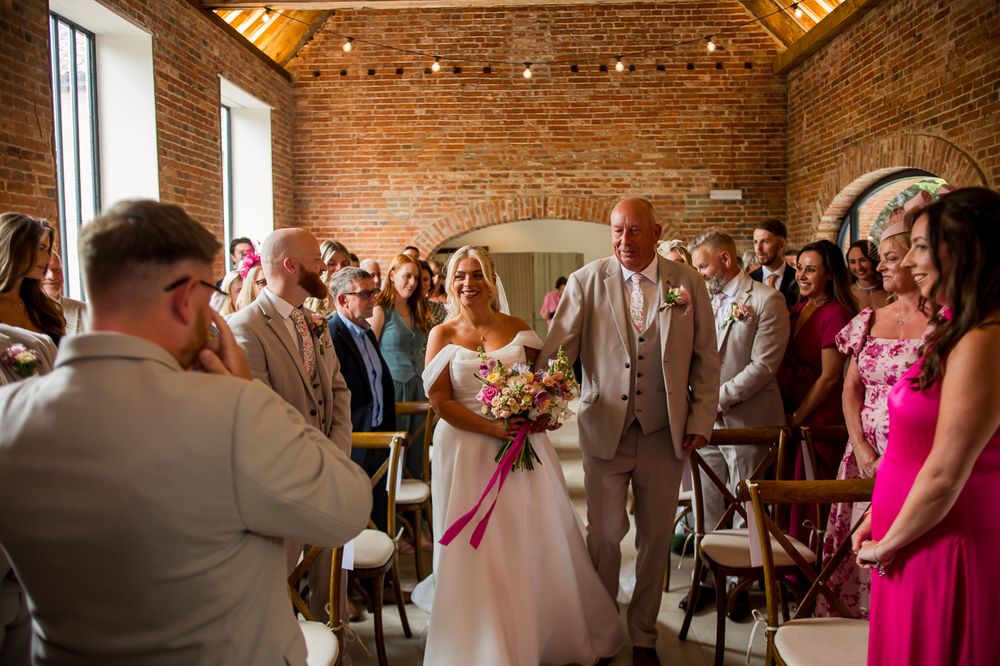 Wedding ceremony moment captured in a historic brick venue with overhead string lighting.