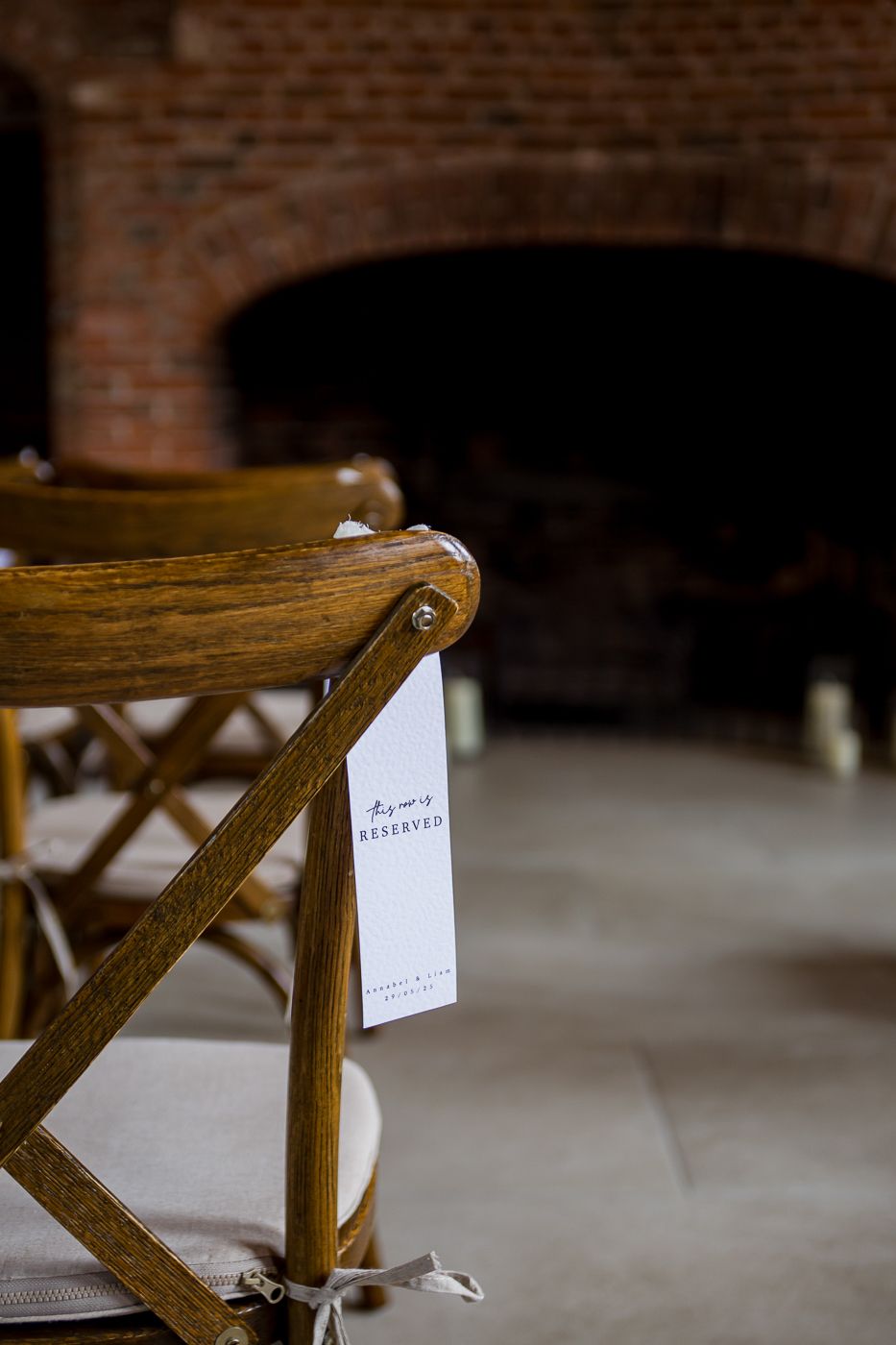 Rustic wooden chairs with small notes attached line up in a brick-walled venue.