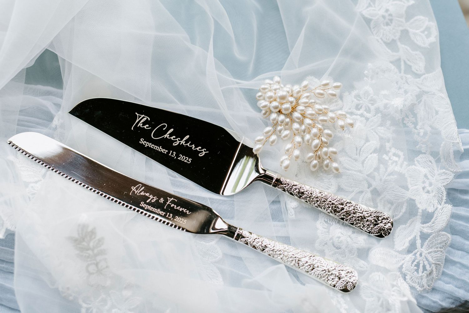 Ornate silver-plated cake server with detailed handle pattern rests on white lace background.
