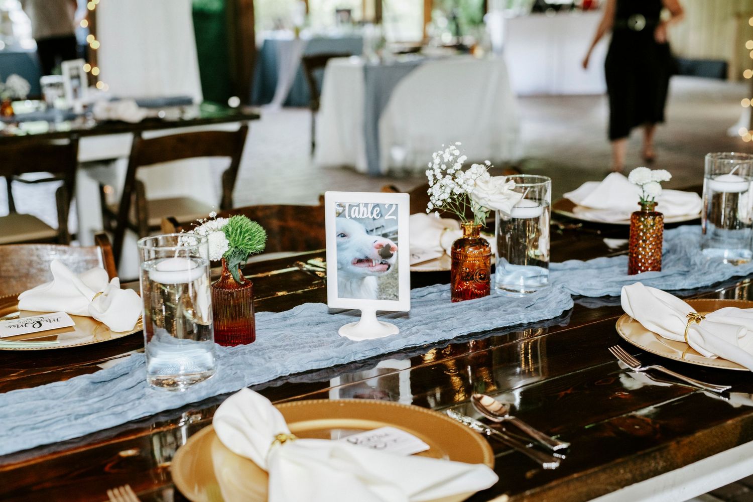 Place settings and glassware arranged on a dark wooden table in a restaurant dining room.