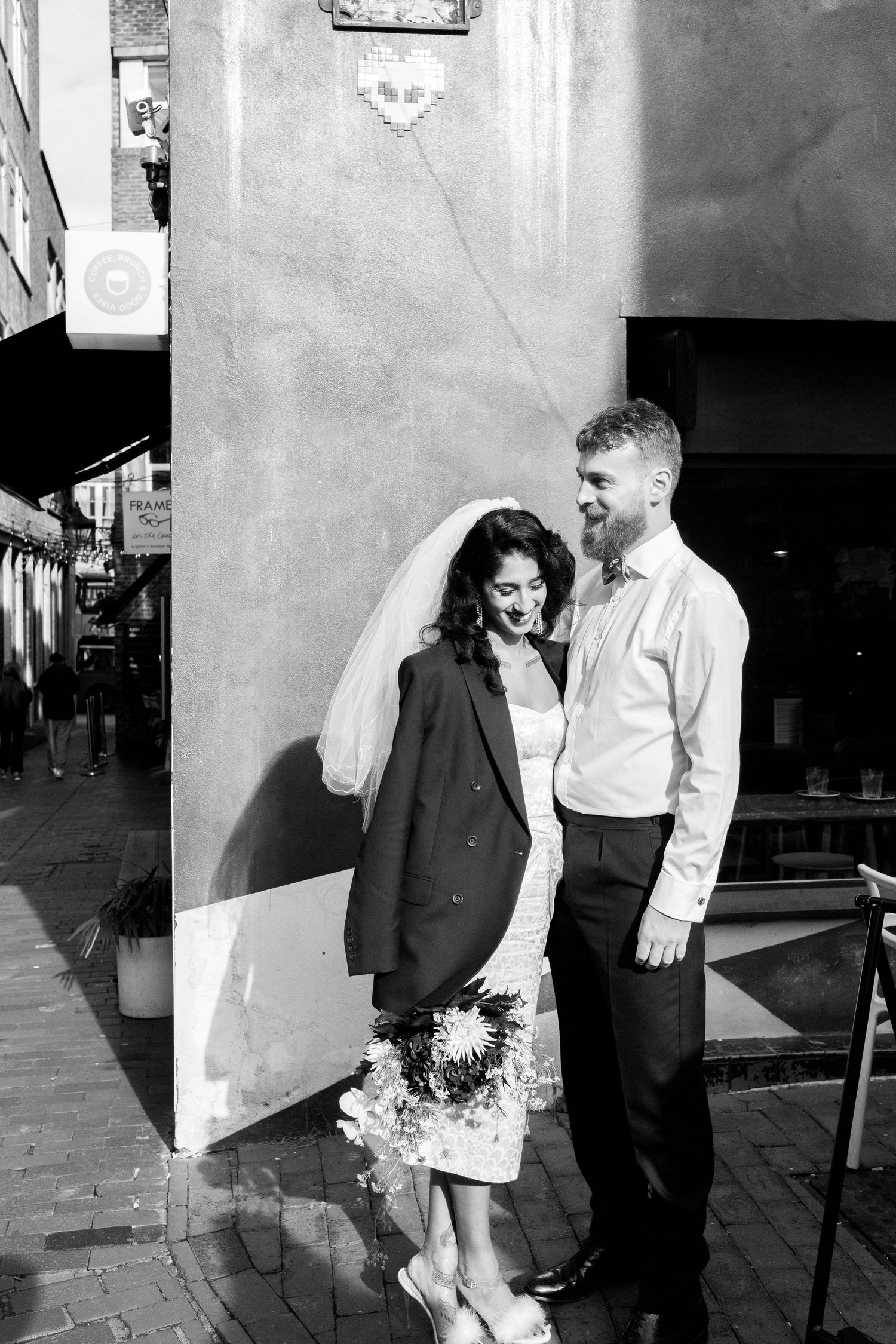 A black and white photo series shows a couple in formal attire sharing romantic moments against a city wall.