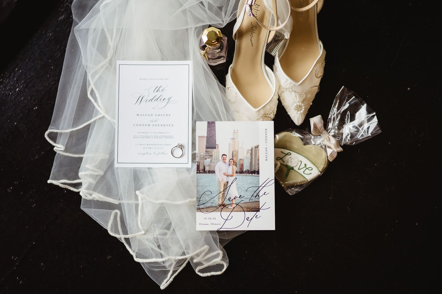 Wedding detail photos including invitation, rings, shoes, and veil arranged on a dark background with elegant styling.
