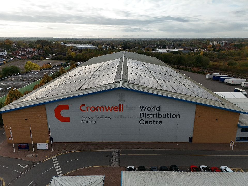 Aerial view of commercial warehouse buildings with white roofs and parking lots in an industrial area.