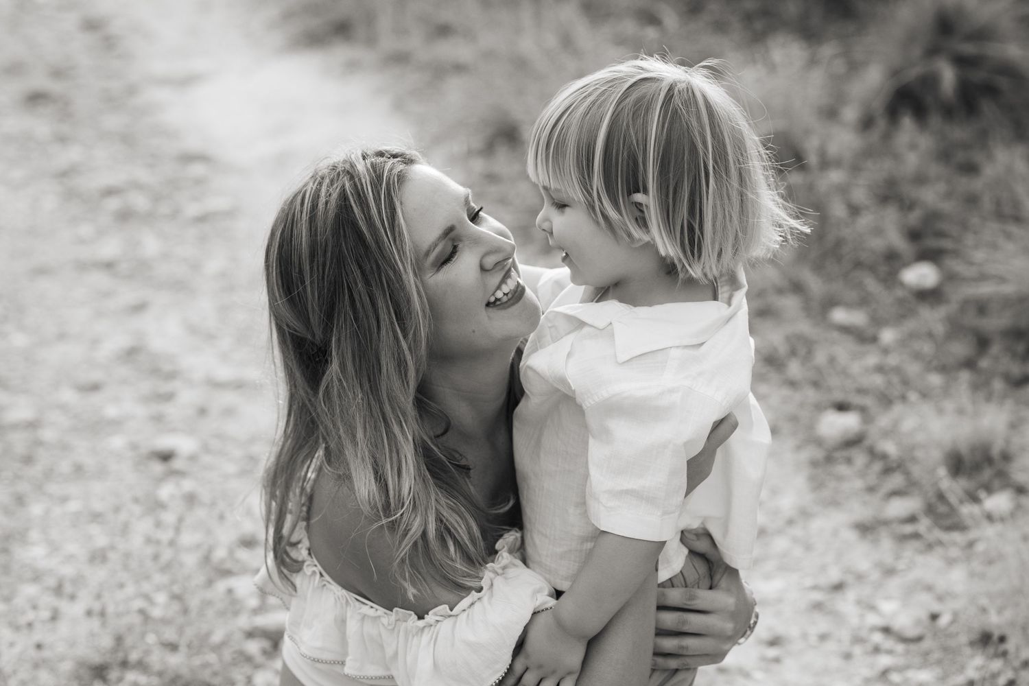Joyful outdoor family photoshoot with white clothing in natural sunlight.