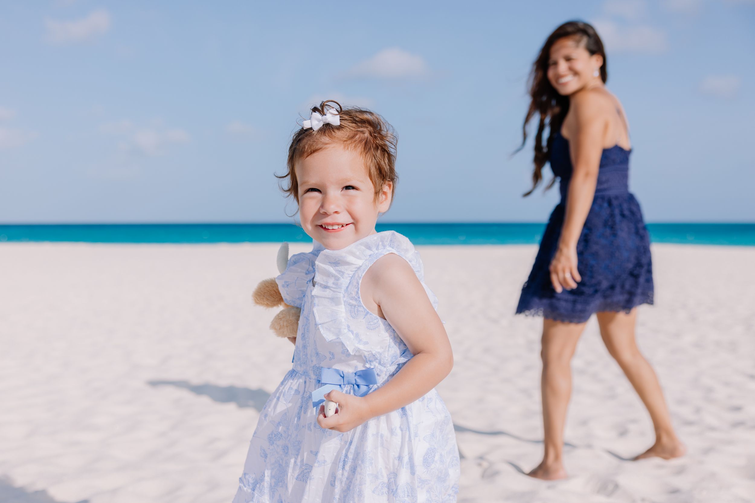 Children playing on pristine white sand beach with crystal blue waters in the background.