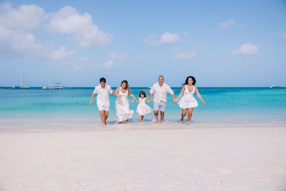 Family dressed in white walking along a beautiful Caribbean beach with crystal clear waters.