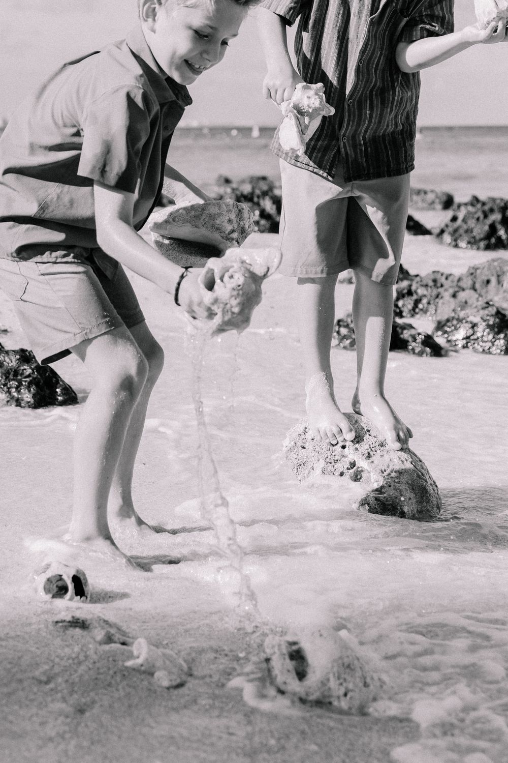 Black and white photo series showing playful splashing in shallow beach water.