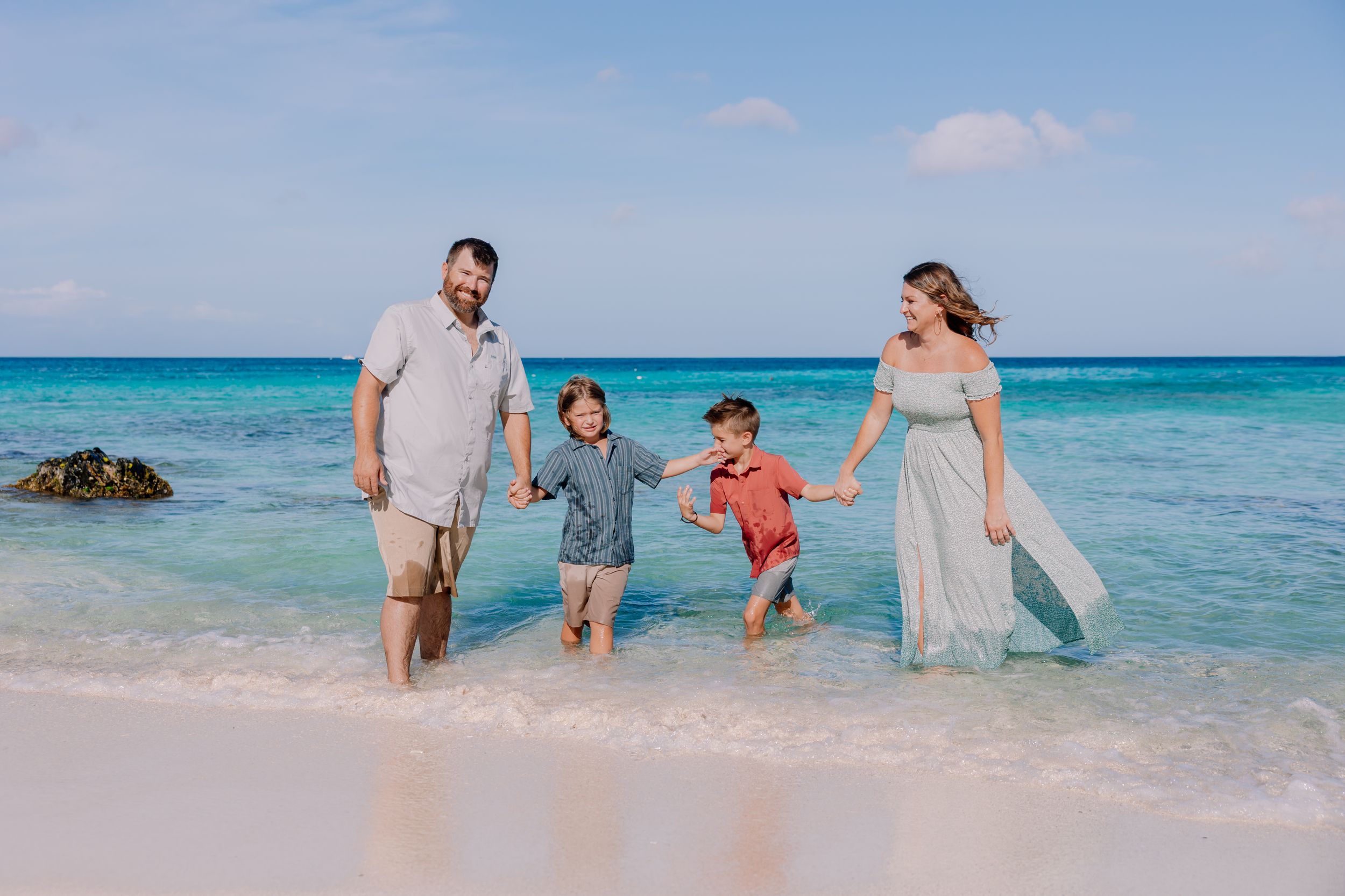 Group enjoying a sunny day walking along the shoreline of a pristine tropical beach.
