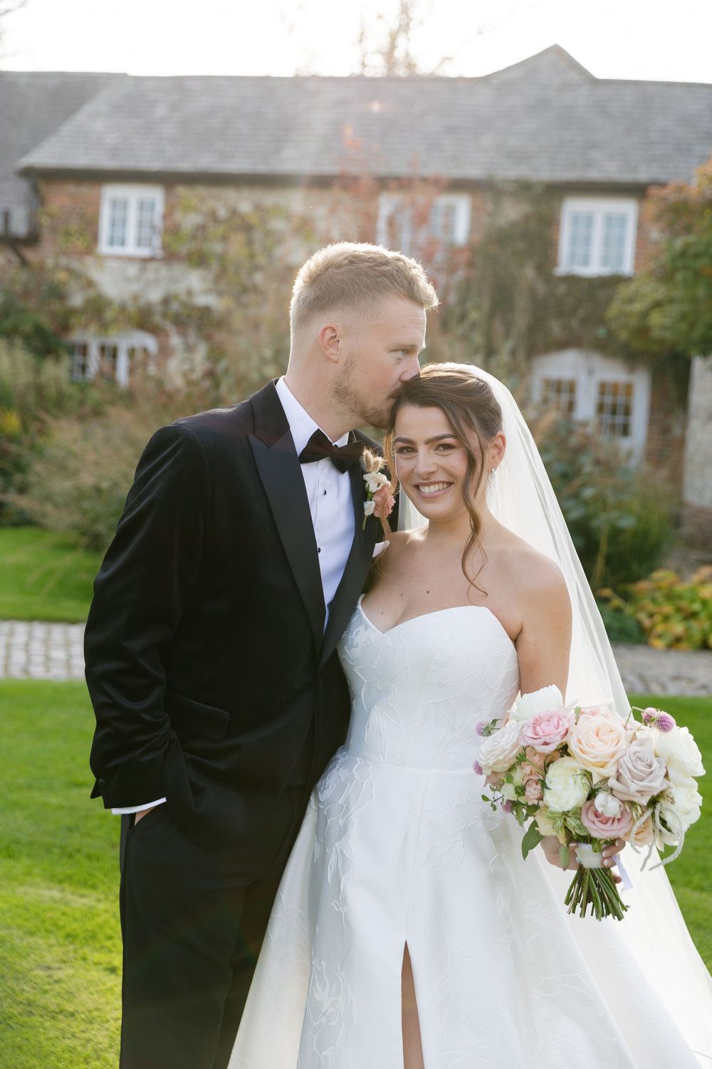 An intimate wedding portrait captured in front of a charming countryside stone house.