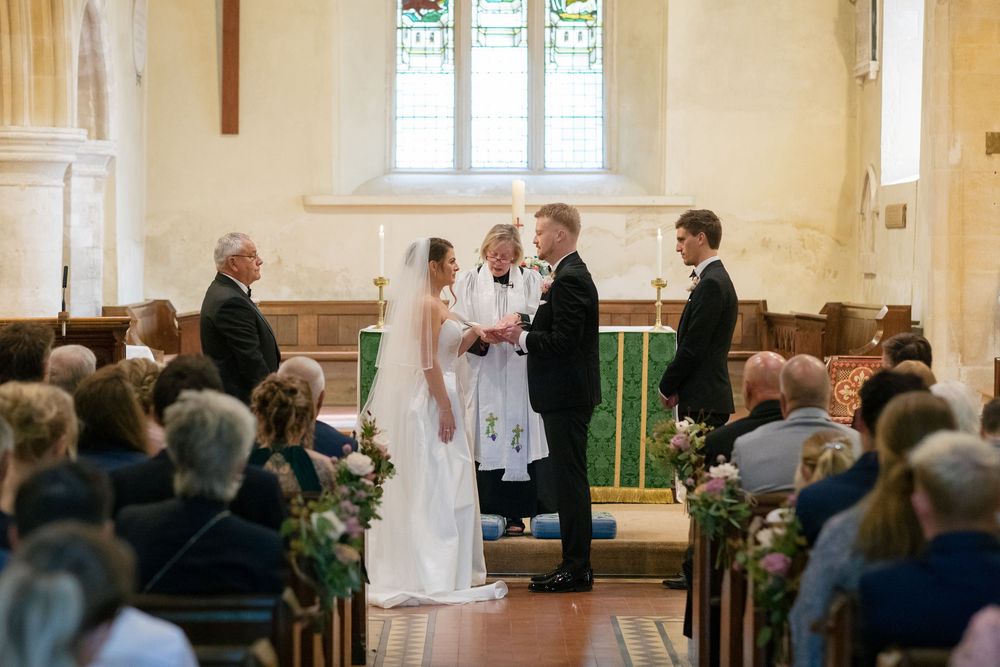 Traditional church wedding ceremony with guests seated in wooden pews under stained glass windows.