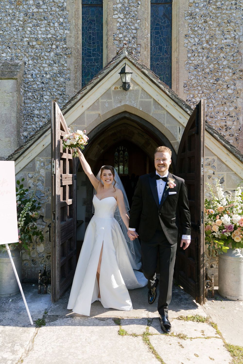 Wedding couple poses for photos outside a traditional stone church entrance with gothic architecture.