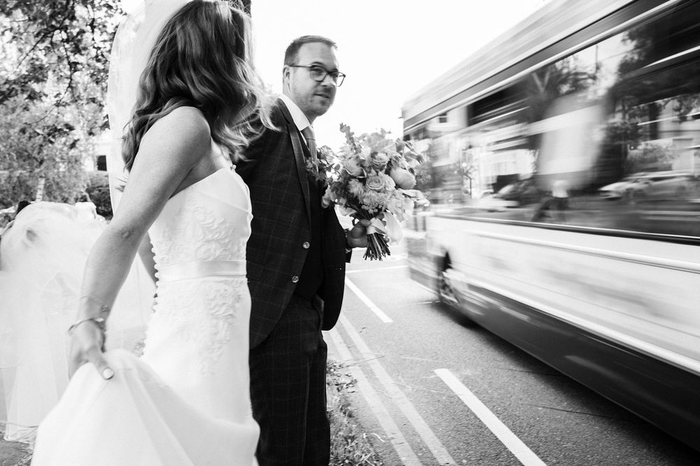 Editorial wedding portrait of bride and groom crossing the street with cinematic motion blur