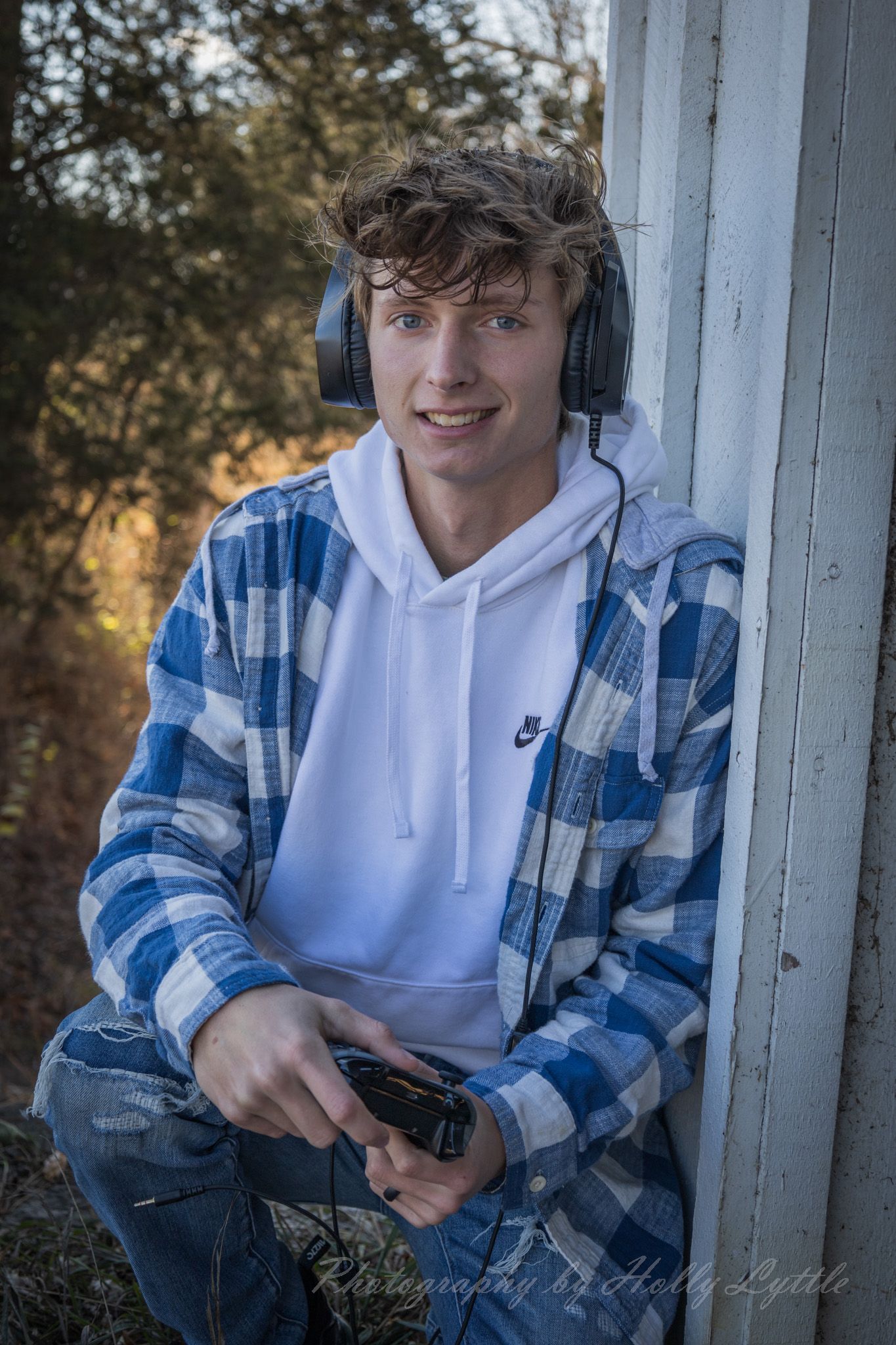 Student in casual plaid shirt and white hoodie poses outdoors in a series of casual portraits.