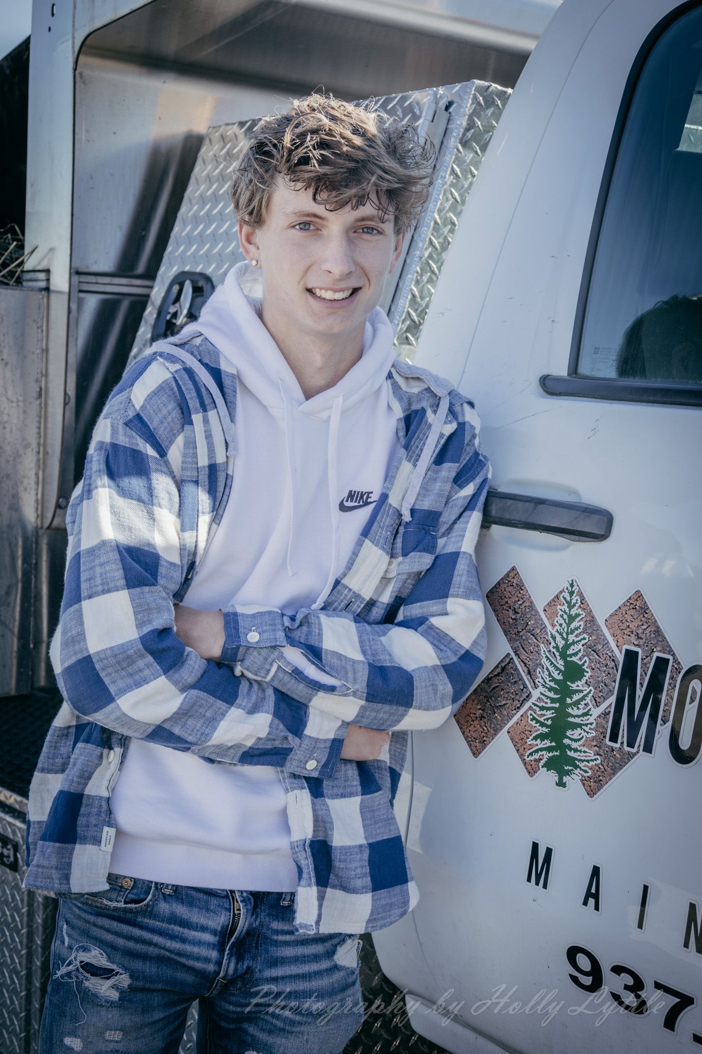 A casual photoshoot featuring blue plaid flannel and a white mail truck in the background.
