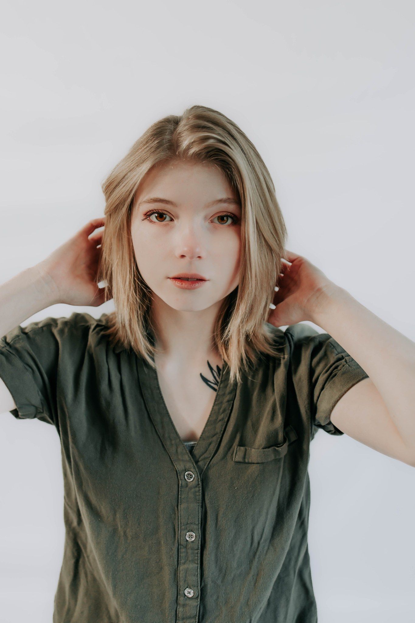 Portrait of someone in olive green button-up shirt against white background.