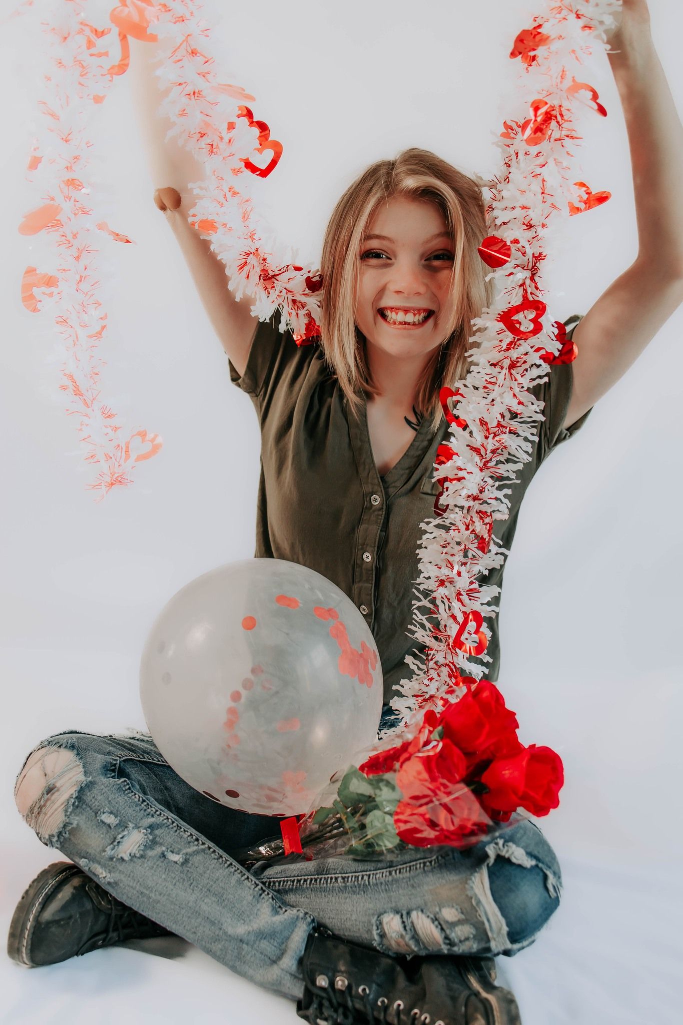Joyful studio portrait with red tinsel decorations and clear balloon against white background.