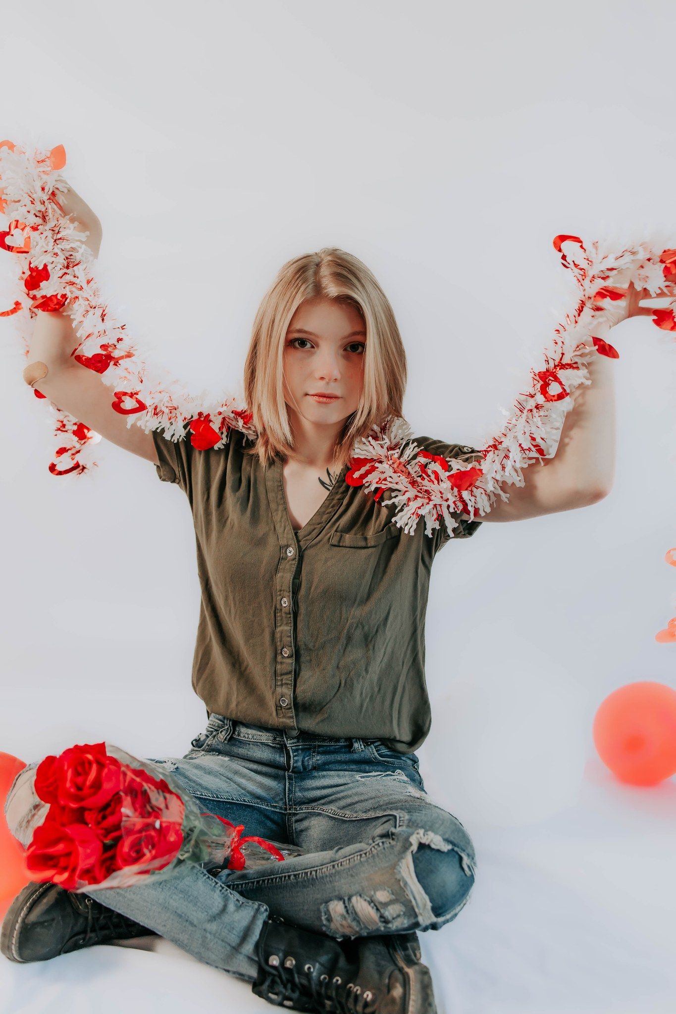 Creative portrait with red tinsel and decorations against white backdrop.