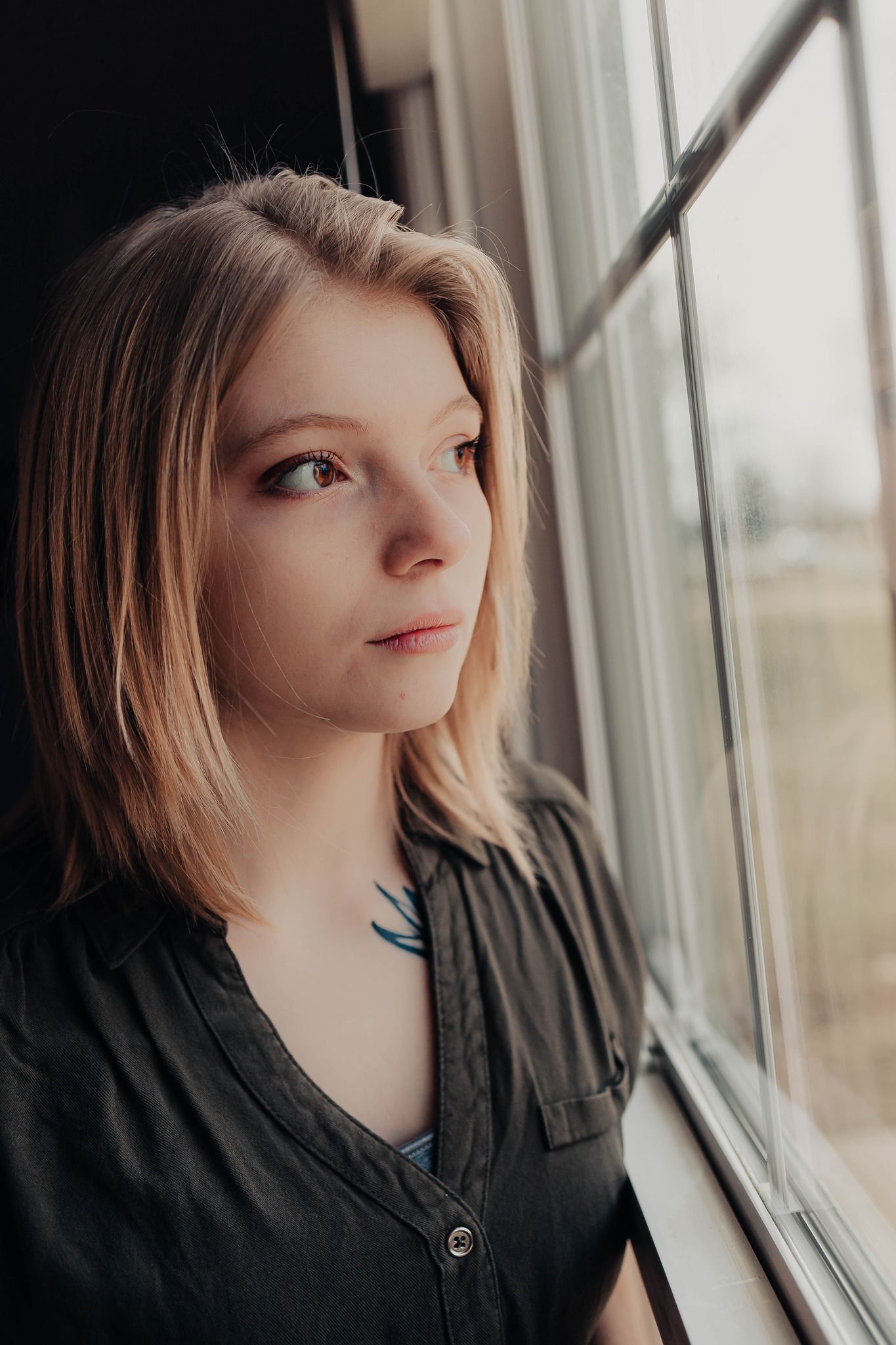 Profile view of someone looking upward by a window with soft natural lighting.