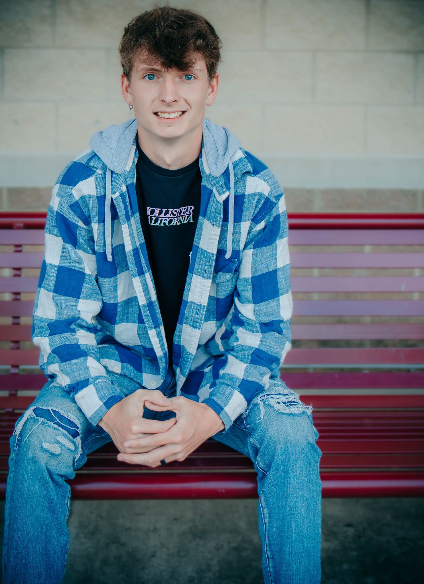 Casual portrait session on red bleachers wearing blue plaid and denim.