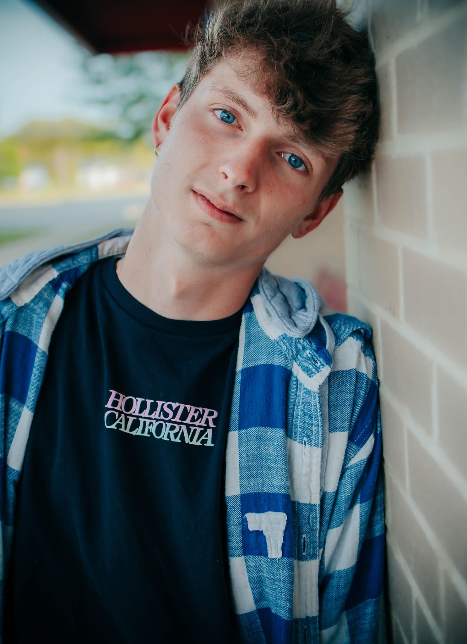Casual portrait series showing person in plaid shirt and dark t-shirt against white wall.