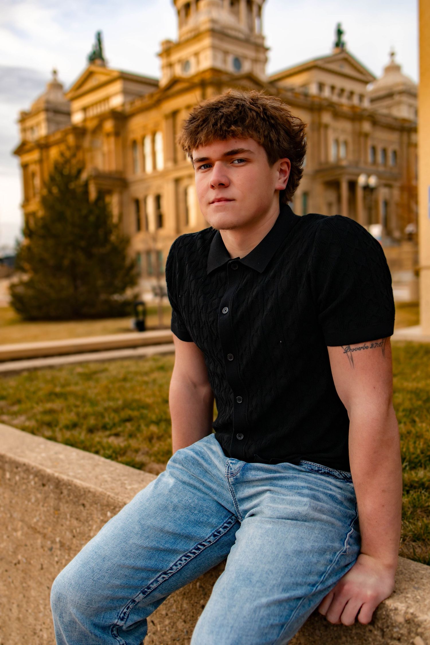 Outdoor senior photos with historic building backdrop and casual modern style.