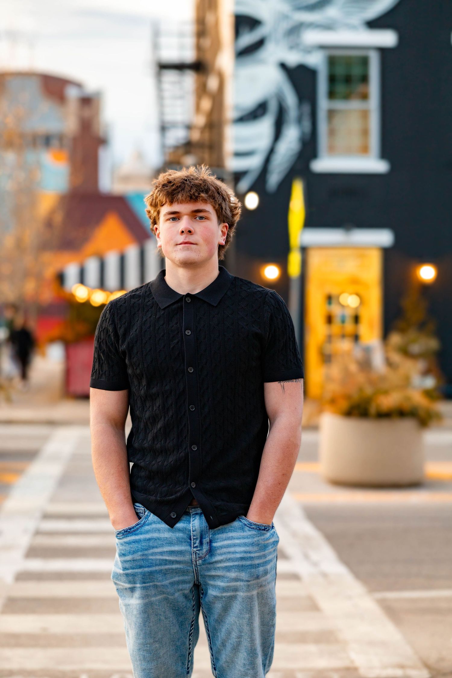 Urban senior portrait session featuring casual outfit with black t-shirt and jeans against downtown architecture.