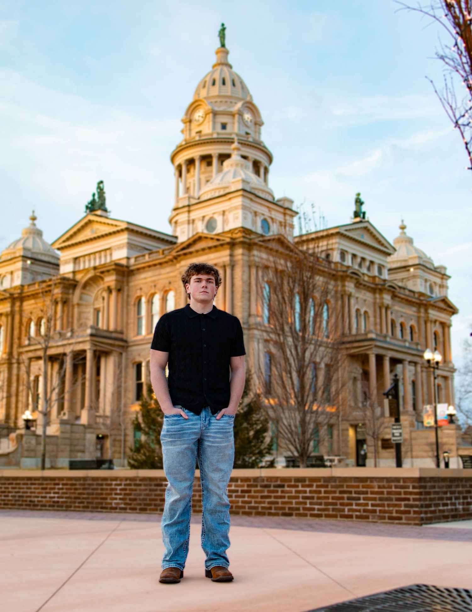 Historic courthouse building with ornate architecture and golden dome stands majestically against blue sky in downtown setting.