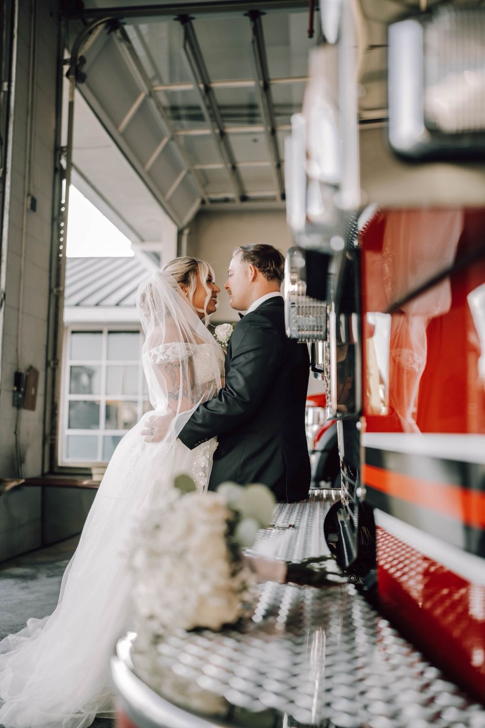 Wedding couple poses for romantic photos in industrial setting with red train car in background.