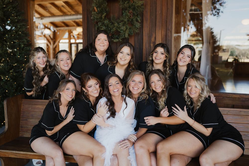 Wedding party poses together on rustic wooden porch with warm lighting at sunset.