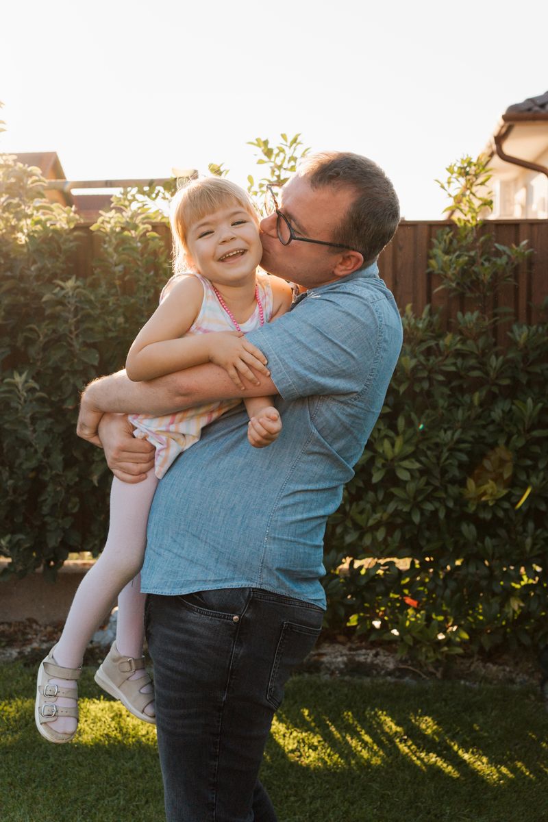 Joyful moment shared between dad and daughter embracing in their Rouse hill home backyard garden during golden hour sunset family photoshoot