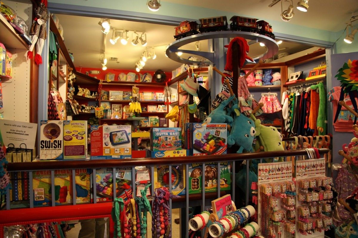 Colorful retail store interior displaying vintage toys, collectibles and memorabilia on shelves with track lighting above.