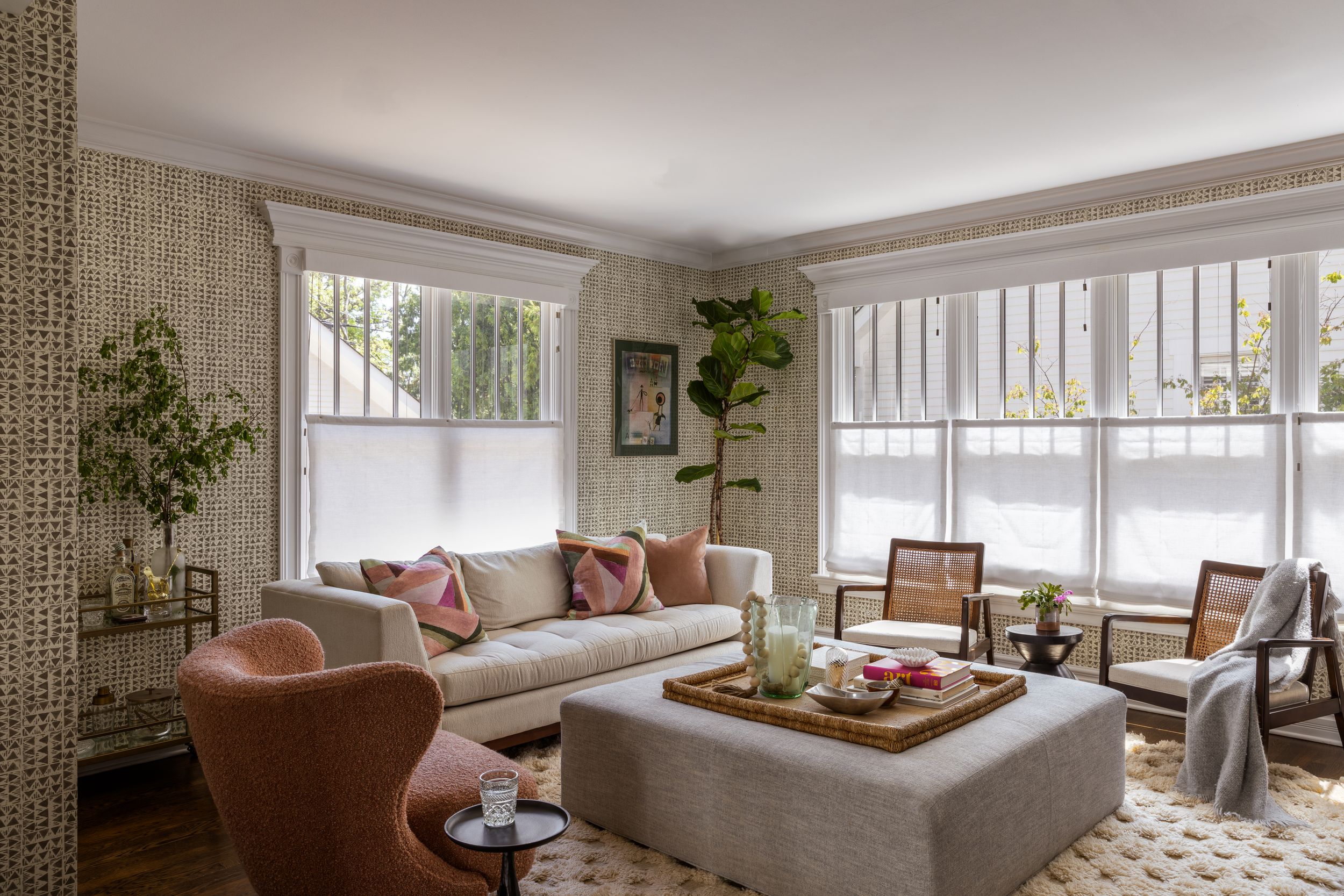 Modern living room interior with gray sectional sofa, large windows, and built-in window seating in neutral tones.