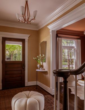 Elegant interior hallway featuring crown molding, white trim, and warm tan walls with multiple doorways and natural light.