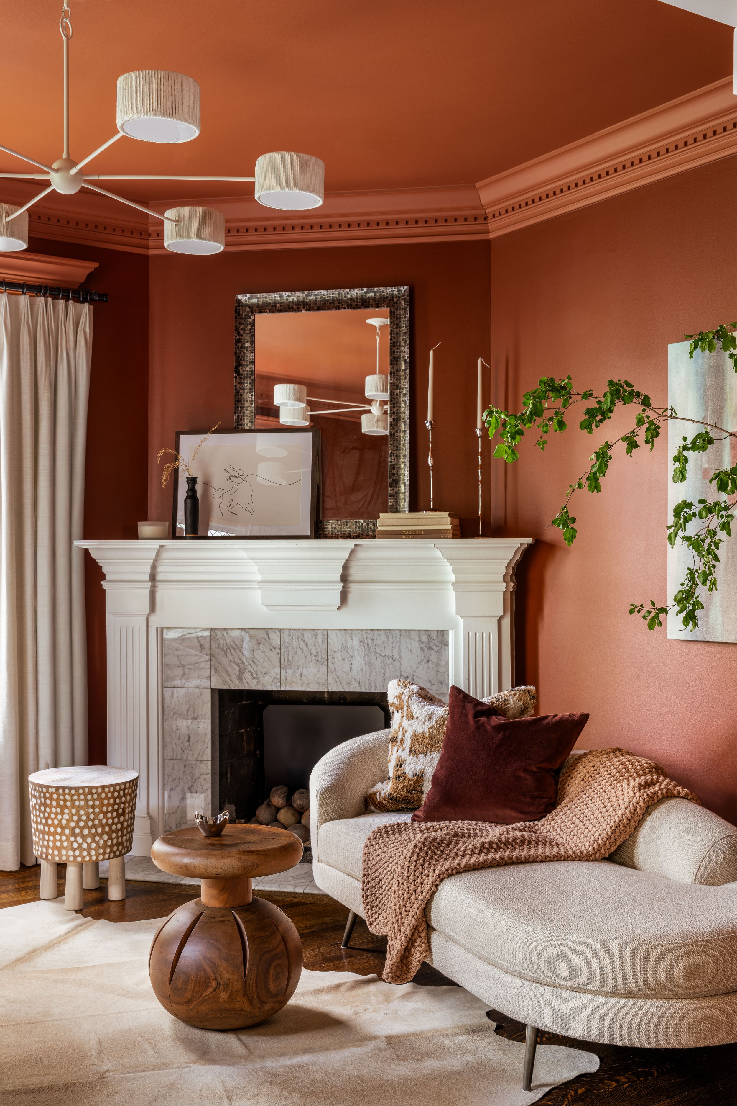 Modern living room with coral walls, white fireplaces, curved lounge chairs, and pendant lighting creates a warm, luxurious atmosphere.