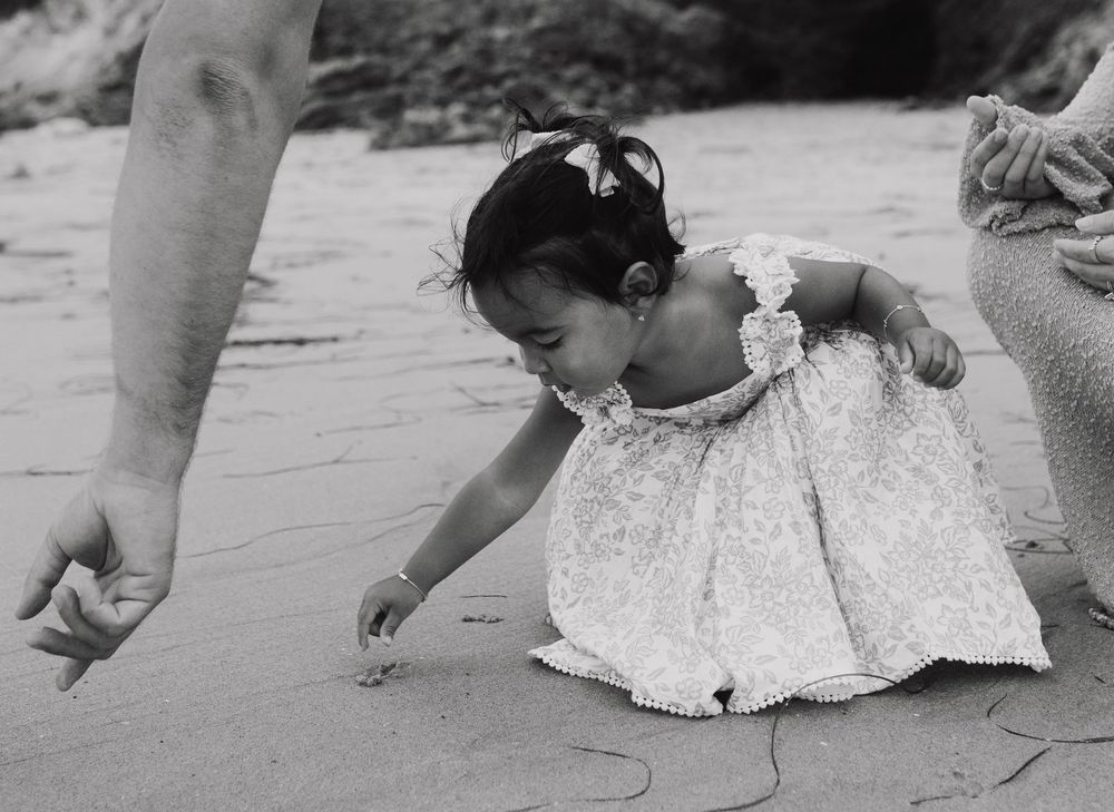 Family members walk together on the sandy beach leaving footprints near the water's edge.