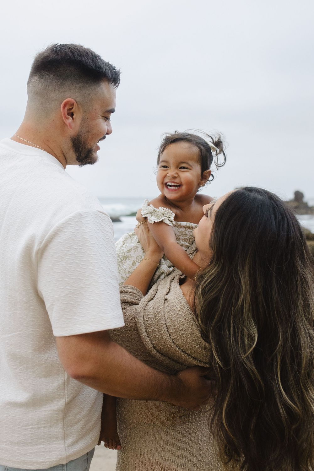 A couple shares joyful moments together in a series of candid beach photos showing their playful interaction.