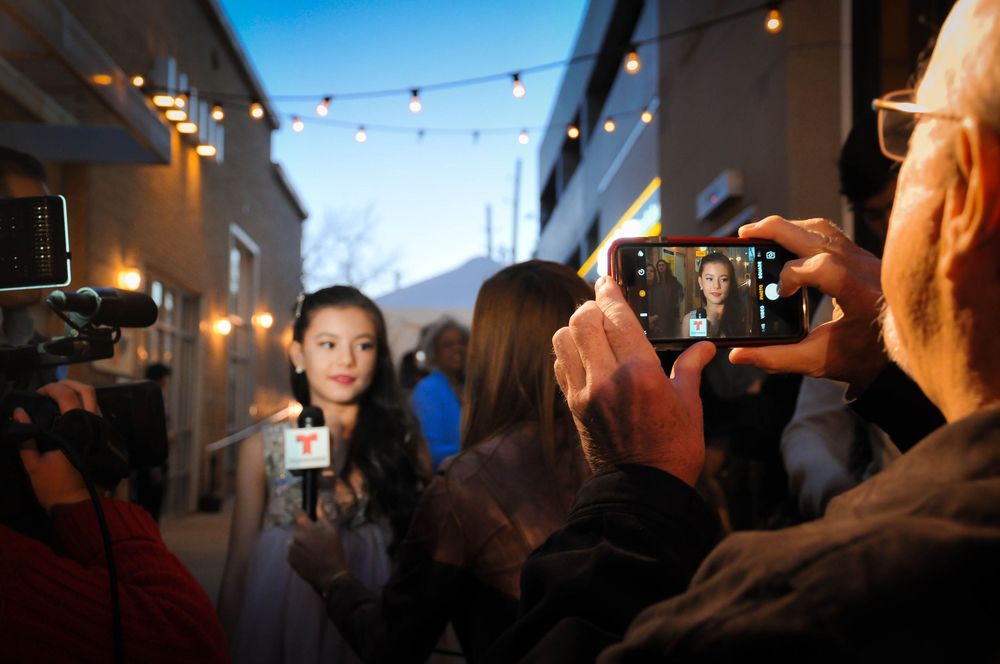 A row of blurred candid photos showing people gathered at an indoor event with string lights overhead.