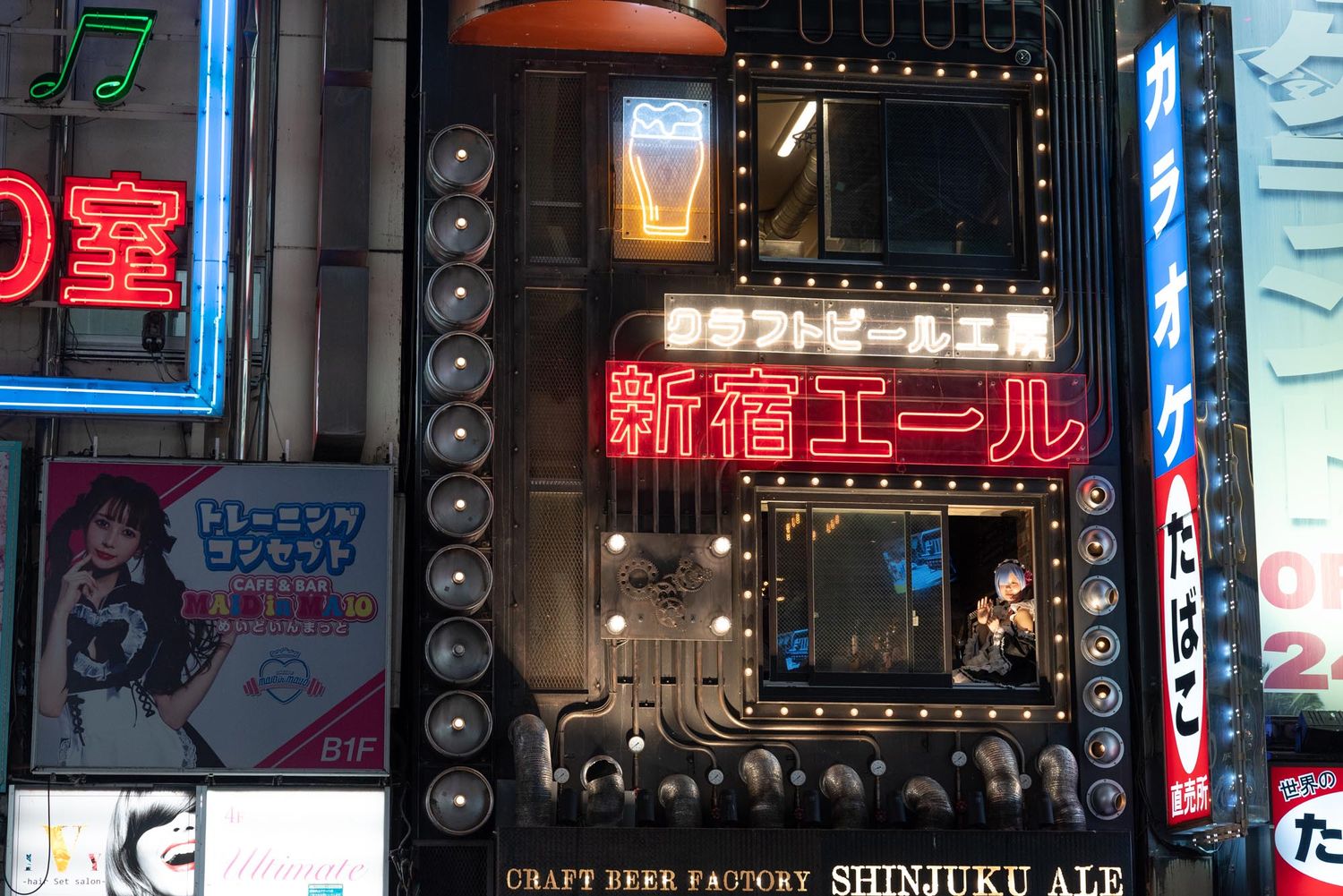 Neon signs illuminate a storefront in Shinjuku with Japanese text and glowing red lettering at night.