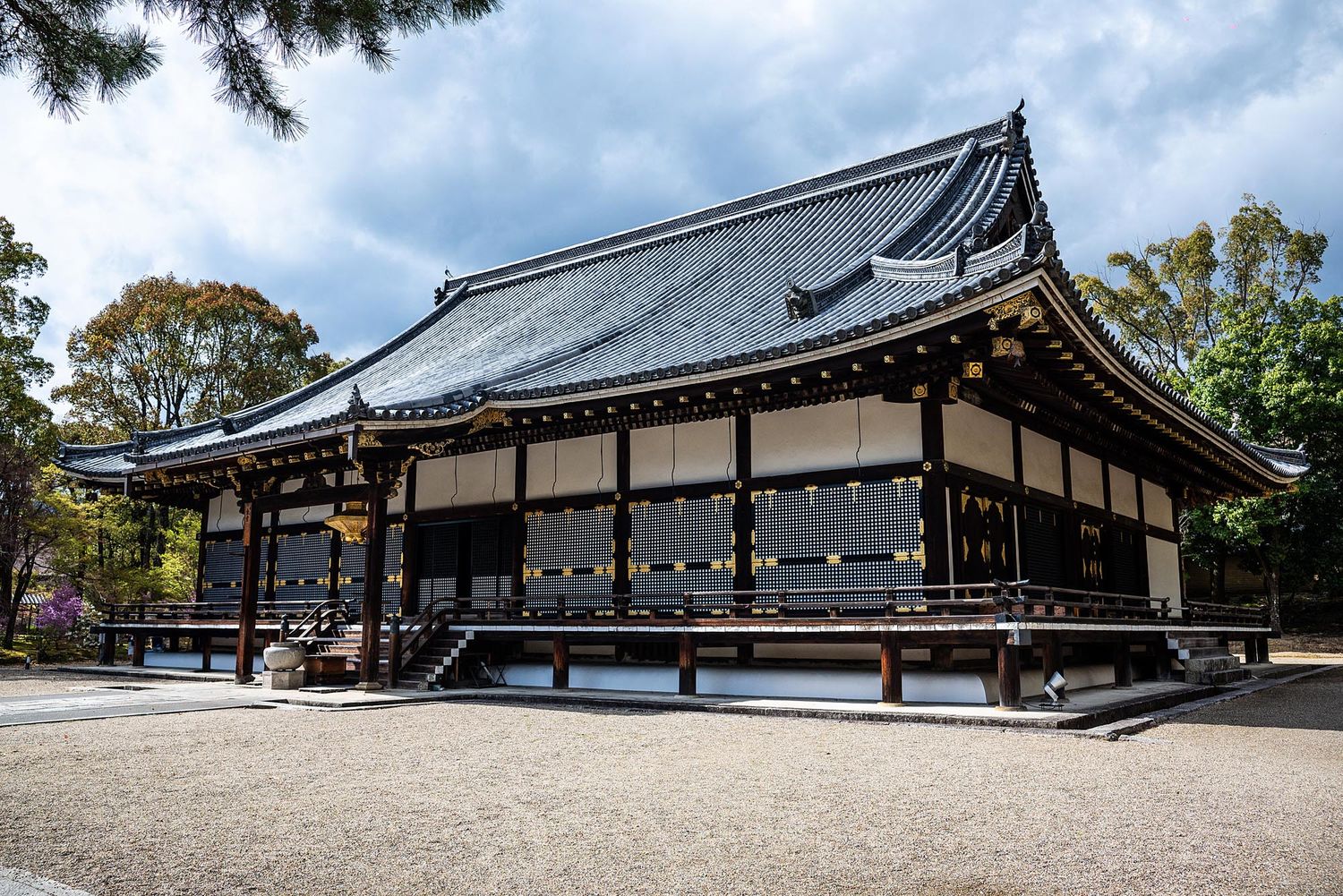 Traditional Japanese temple buildings with dark wooden structures and sloped roofs stretch across a panoramic view.