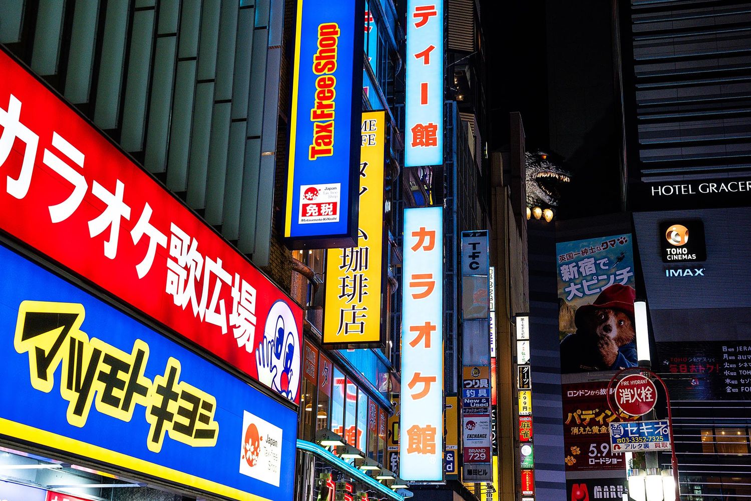 Colorful neon signs and advertisements illuminate a street in Tokyo's entertainment district at night.