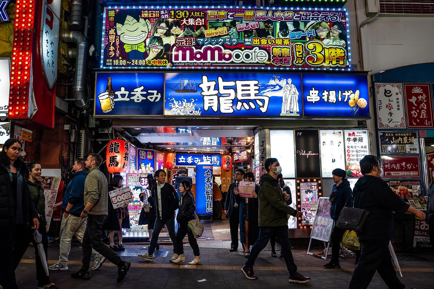 Vibrant neon signs illuminate a busy nighttime street in South Korea's entertainment district.