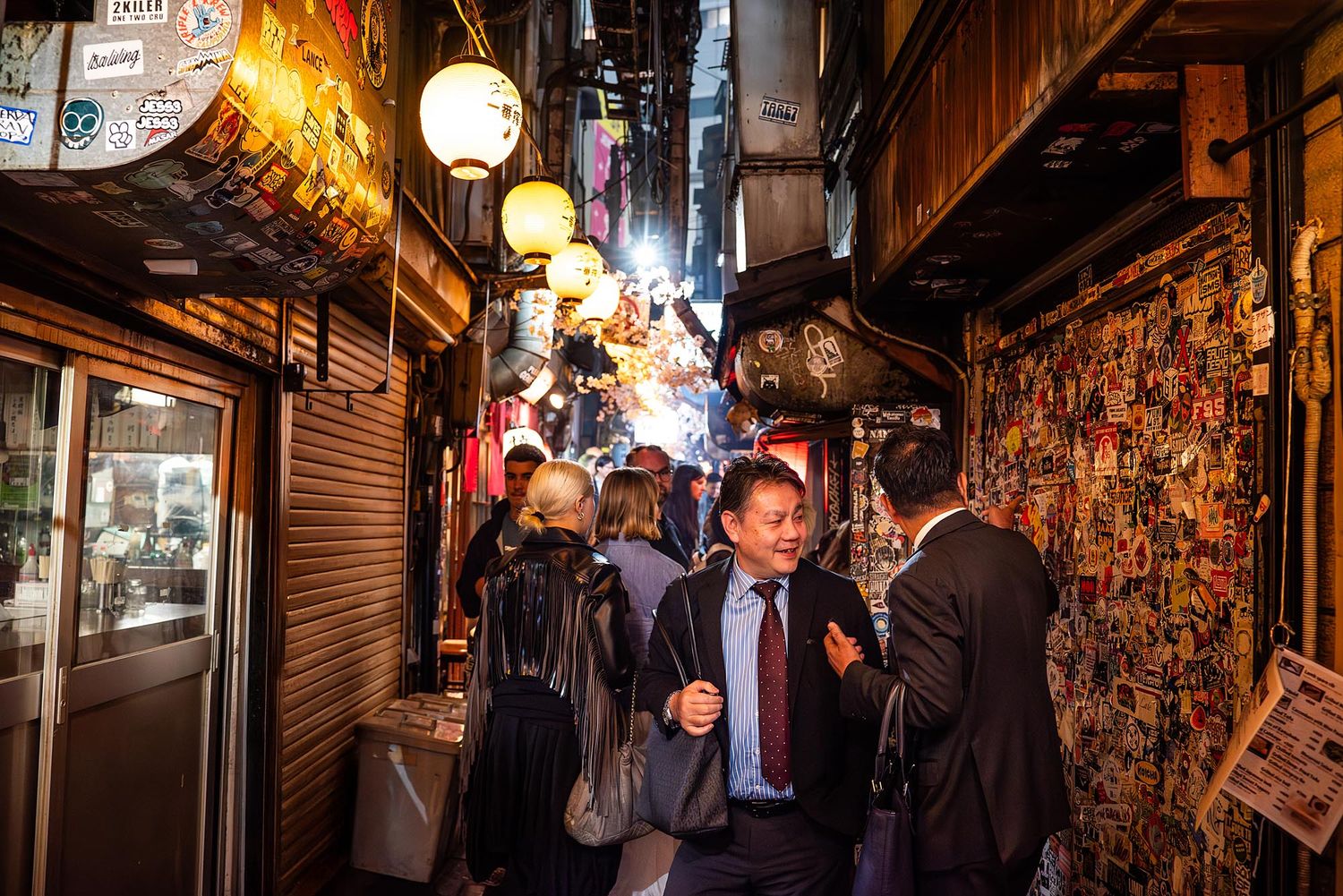 Narrow alleyway in Japan lined with traditional lanterns and glowing signs creating a moody nighttime atmosphere.