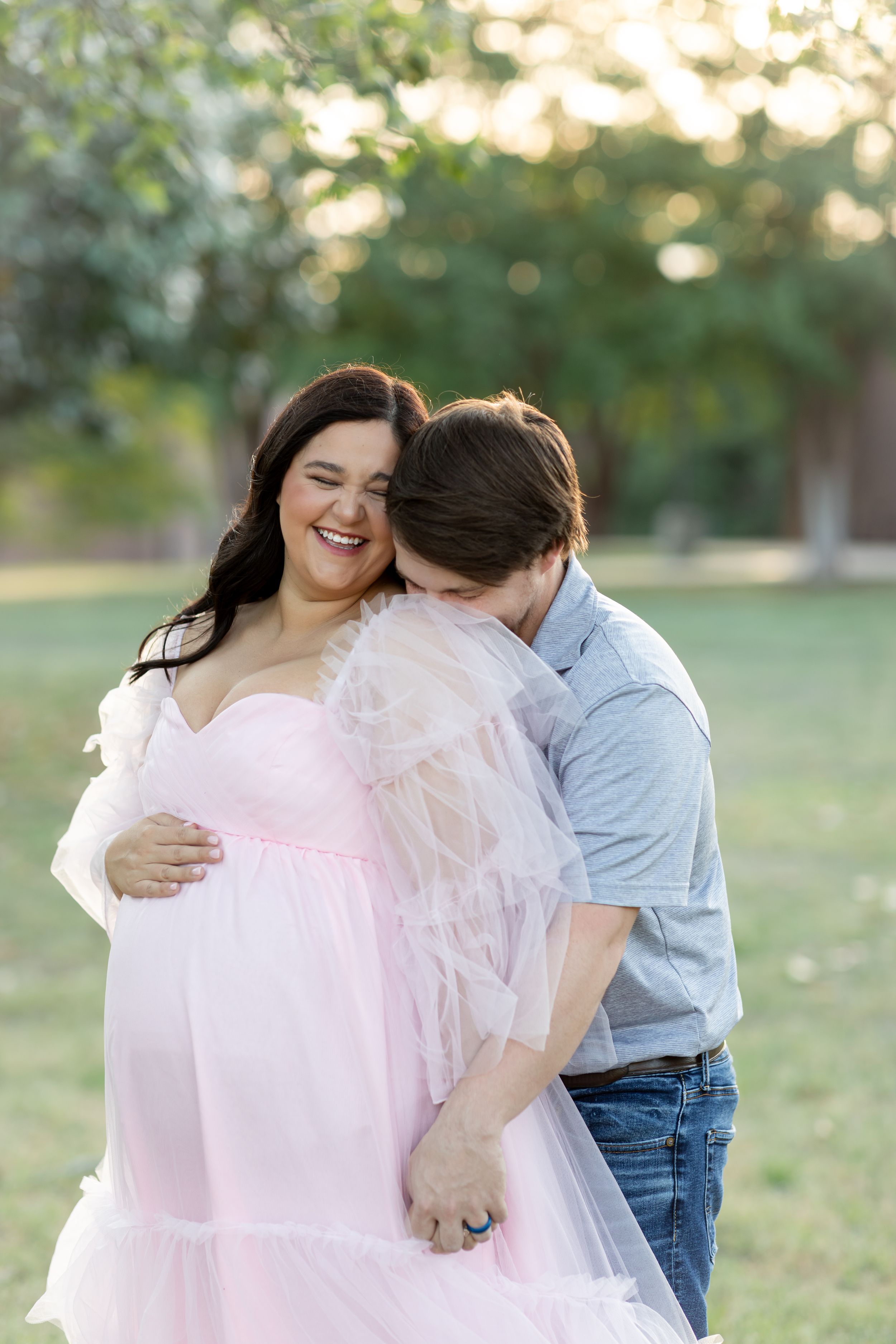Joyful outdoor maternity moment captured in golden evening light.