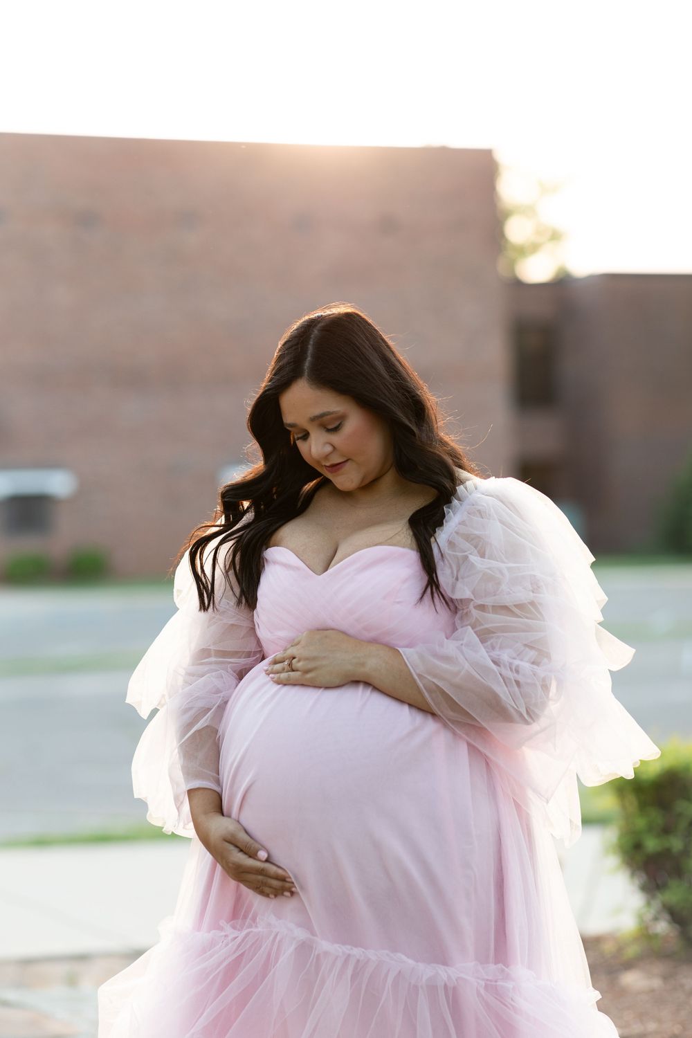 Sunset maternity portrait featuring pink tulle gown and soft natural lighting.