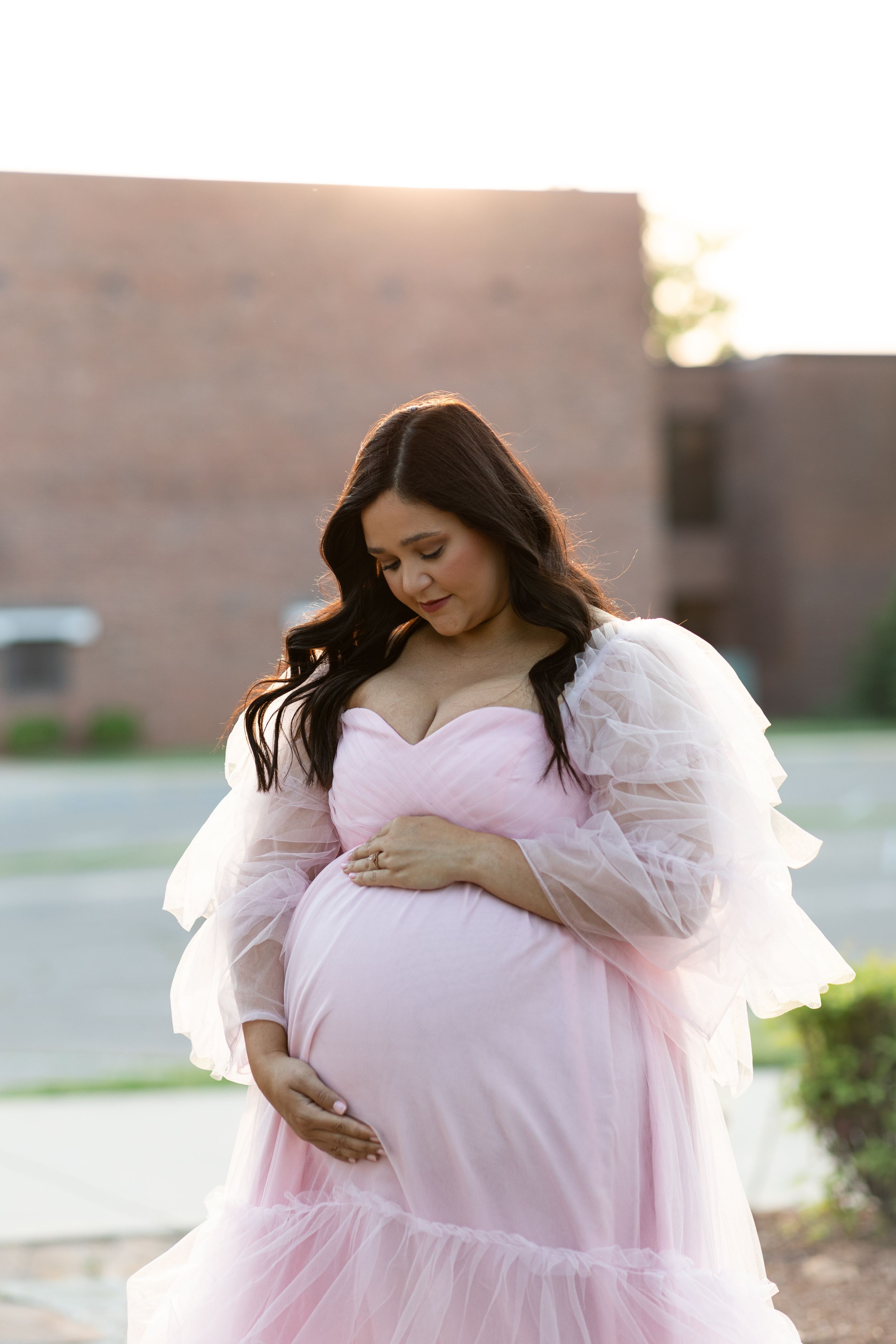 Sunset maternity portrait featuring pink tulle gown and soft natural lighting.