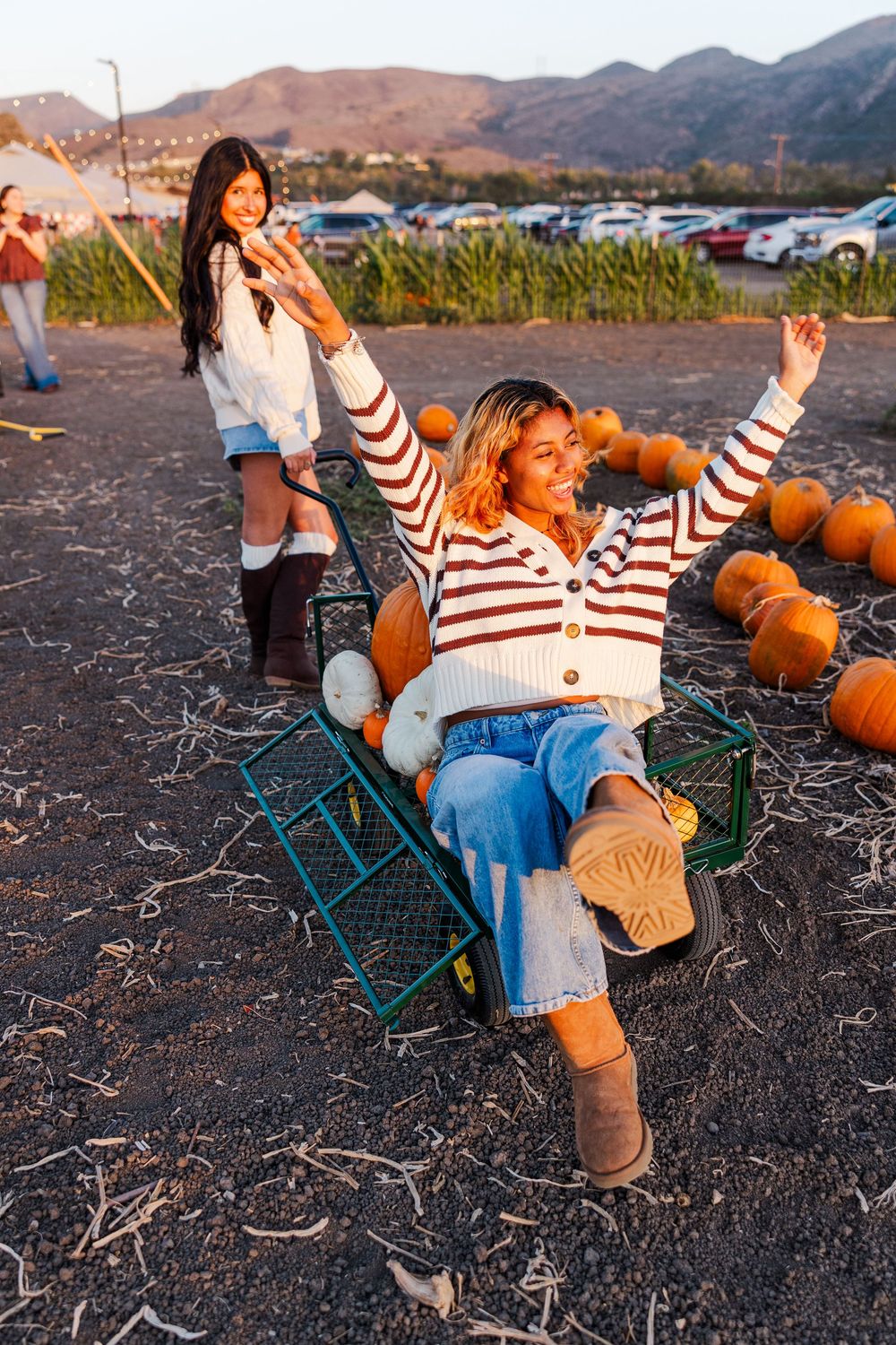 Person relaxing in camping chair at pumpkin patch with mountains in background at sunset.