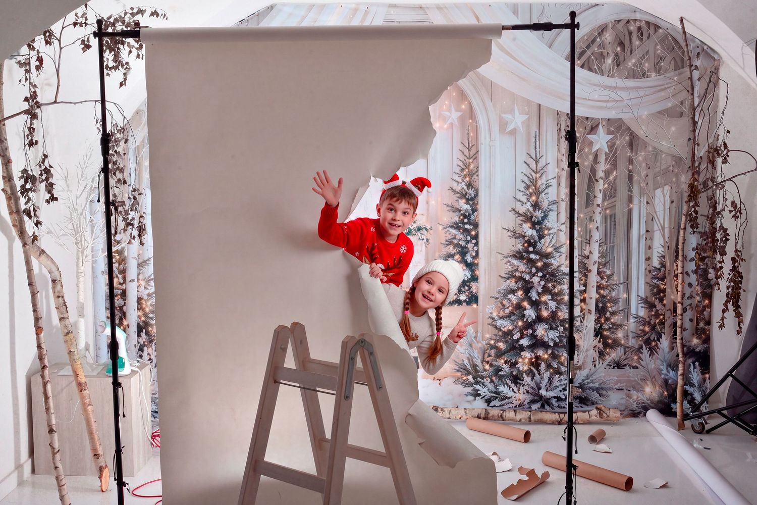 Holiday photo setup with Christmas trees, gifts and white snowflake decorations.