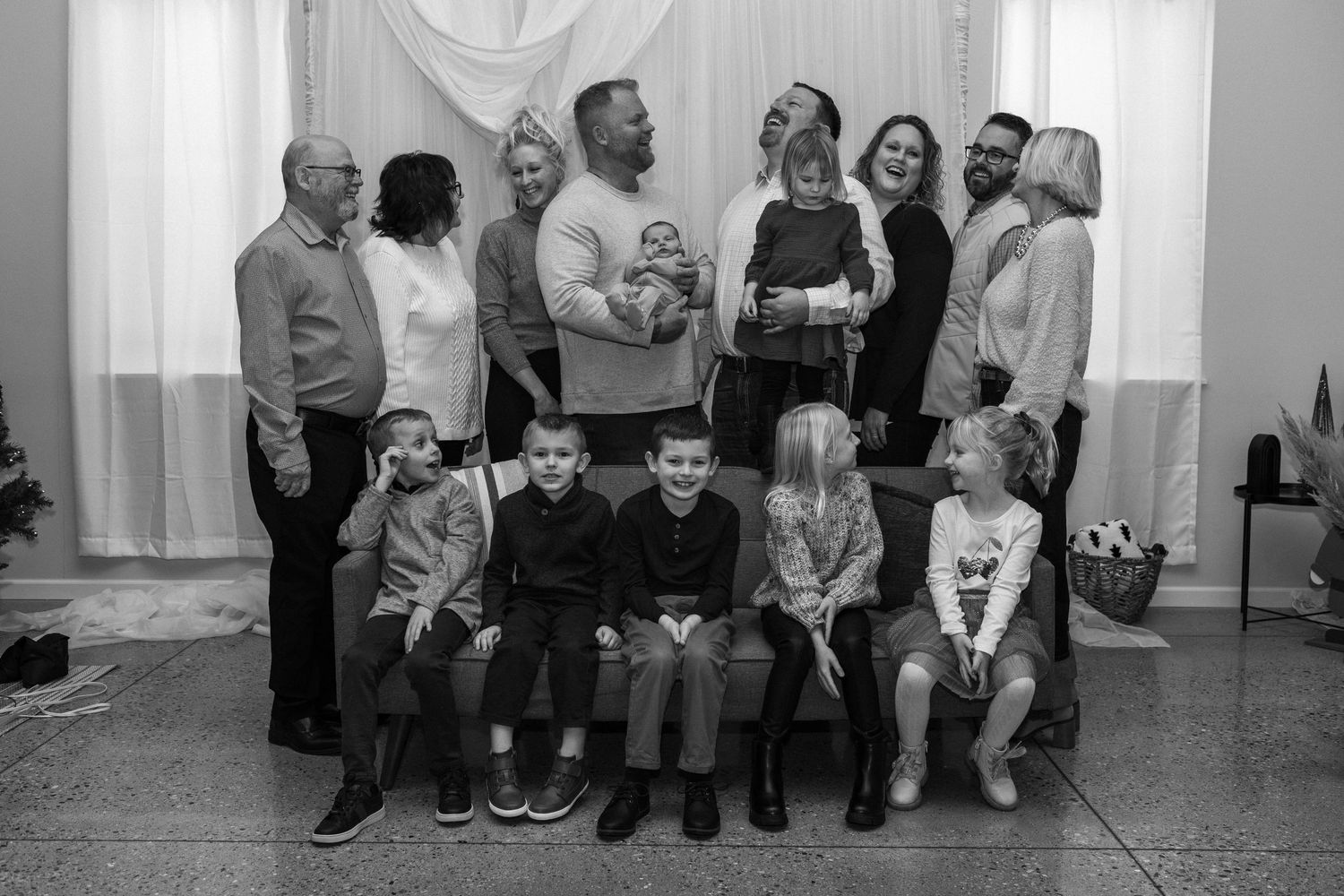 A group of people sitting in a row on chairs against a white wall.
